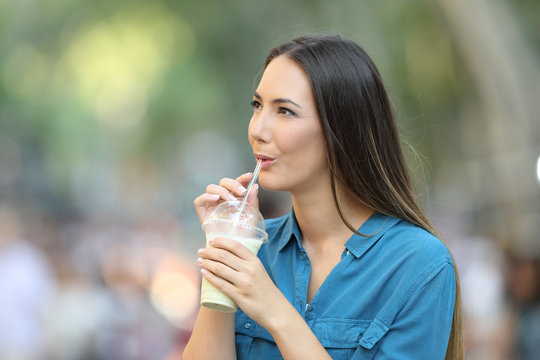 Woman drinking a smoothie looking at side
