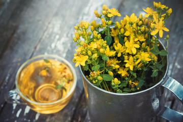  St Johns wort flowers in a large retro mug and Healthy hypericum tea - not in focus.