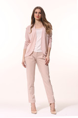young caucasian business woman executive posing in designer formal summer pink powder pant suit high heels stiletto shoes full body length isolated on white