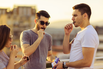 Three Happy Friends Talking While Eating Chocolate. Young and careless concept.