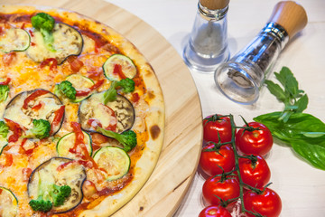 appetizing vegetarian pizza with spices and basil leaves on a white table, flat lay