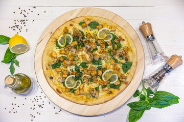 appetizing pizza with prawns, lemon, olive oil and spices on a white table, flat lay