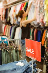 Woman looking clothes on discount in the shopping mall, seasonal sale concept
