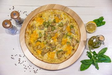 appetizing pizza with chicken and pickled cucumbers, spices and olive oil on a white table, flat lay