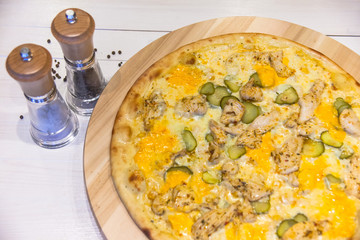 appetizing pizza with chicken and pickled cucumbers and spices on a white table