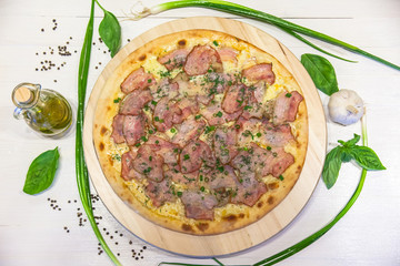 appetizing pizza with bacon, green onions and olive oil on a white table, flat lay