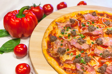 appetizing pizza with bacon, bell pepper and basil on a white table
