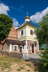Fototapeta na wymiar Old bell tower and 15th century St. Michael fortified church at summer in Synkovichi, Grodno region, Belarus.