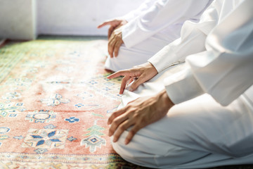 Muslim men praying in Tashahhud posture - obrazy, fototapety, plakaty