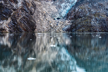 Water reflections of rocks and a glacier.