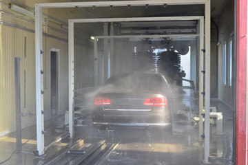 Auto being washed in a high pressure rinse arch in an automatic car wash facility