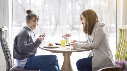 Two female friends laughing in a cafe face to face talking making notes eating salad