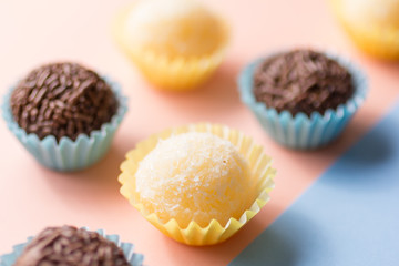 Brazilian sweets: Beijinho and Brigadeiro. Children birthday parties. Candy balls in a straight line. Colorful background.