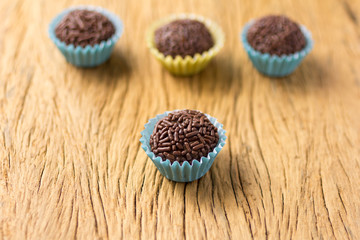 Brigadeiro is a chocolate truffle from Brazil. Cocoa and sprinkles of chocolate. Children birthday party sweet. Selective focus. Rustic wooden table.