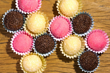 Brigadeiro Beijinho and Bicho de Pe: sweets from Brazil. Child birthday party. Overhead of candy ball on rustic wood table.