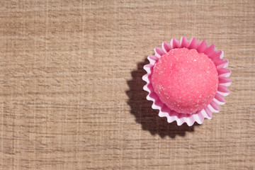 Bicho de pe is a strawberry flovoured brazilian candy. Children birthday party sweet. Flat lay design of candy ball over wood.