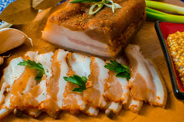 Pork lard with garlic, pepper and herbs on a wooden board