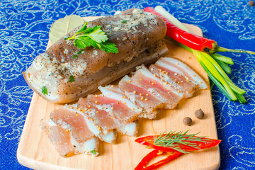 Pork lard with garlic, pepper and herbs on a wooden board