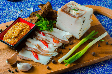 Pork lard with garlic, pepper and herbs on a wooden board