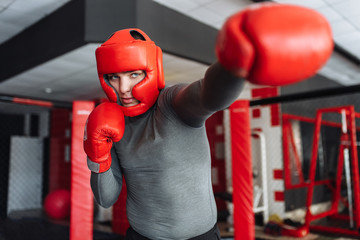 Boxing glove close-up, male boxer engaged in training in the gym, in a cage for a fight without...