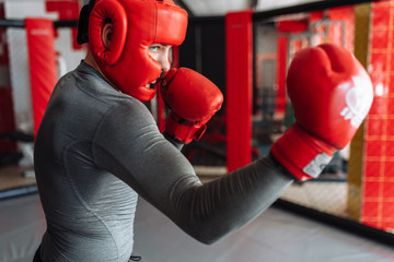 Male boxer engaged in training in the gym, in a cage for a fight without rules, Boxing coach