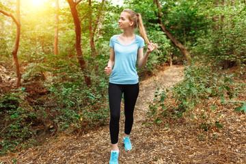 Beautiful girl running through the woods, morning jog, athlete