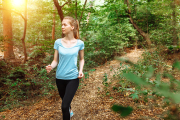 Beautiful girl running through the woods, morning jog, athlete