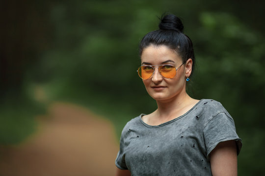 Brunette Girl In Green Shirt And In Yellow Glasses In The Forest In Summer.