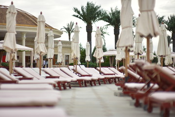 Summer holiday resort. Сhaise-longue and umbrellas beside of pool