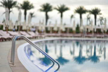 Summer holiday resort. Сhaise-longue and umbrellas beside of pool