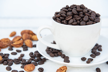 Cup of coffee with coffee beans on white wooden table