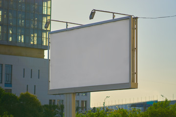 billboard white blank at sunset in the city. preparation for fitting advertising.