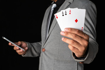 Businessman holding ace card and smartphone isolated on black