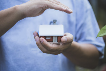 Insurance house concept, scandinavian house model with man 's hand, protecting your new property.
