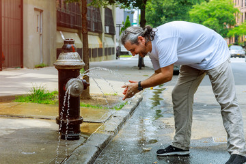 middle-aged man during a strong heat temperature is refreshed with Fire hydrant water