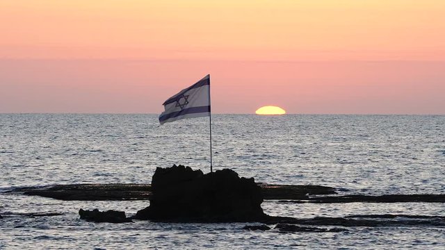 Israel Flag Waving At Sunset. Rock in Mediterranean Sea