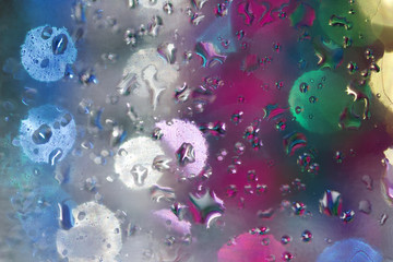 Fototapeta na wymiar Multi color defocused macro abstract of water droplets on glass surface with illuminated background bokeh