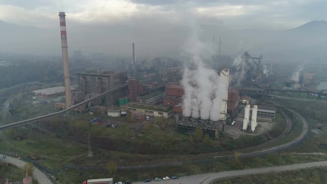 Panoramic drone shot of cooling towers and huge steel factory, causing massive air pollution in mountain valley near Zenica city, global warming climate change, Bosnia and Herzegovina, Europe
