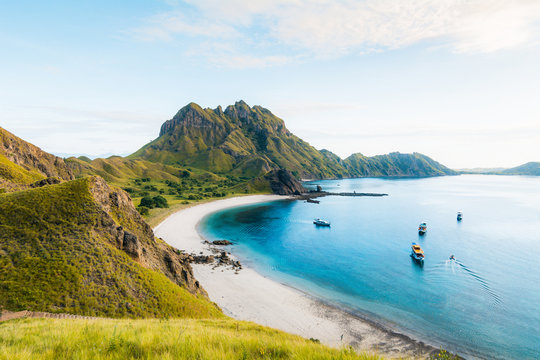 Coast view of Padar Island in a cloudy morning with blue water surface and tourist boats, Komodo Island (Komodo National Park), Labuan Bajo, Flores, Indonesia