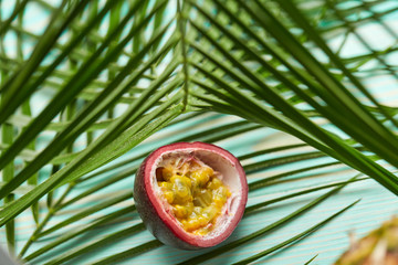 passion fruit and tropical palm leaves on green background.