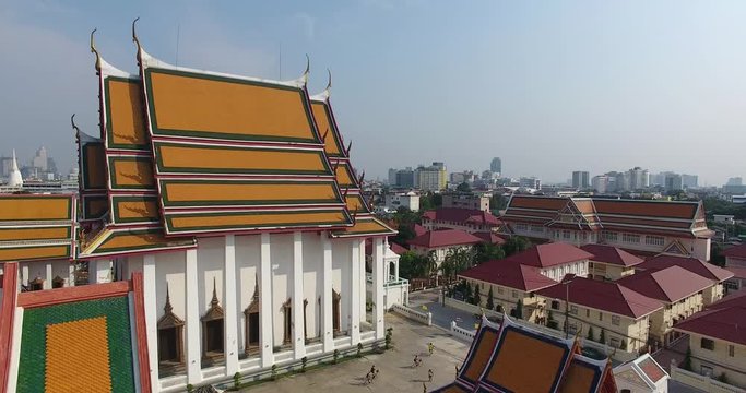 Aerial shot of cyclists near a temple with the Bangkok skyline.