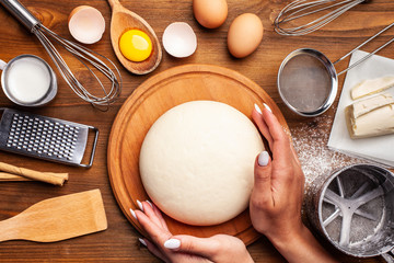 Concept for bakery, restaurant, cafe, production. Hands working with dough on a wooden table. Next...