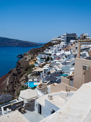 Fototapeta na wymiar Scenic view of traditional cycladic Santorini houses on small street with flowers in foreground. Location: Oia village. Holidays background. Santorini, Greece, june 2018