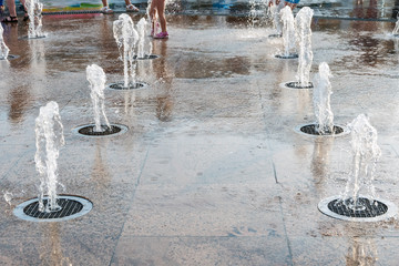 Happy children have fun playing in water fountains. Hot summer.