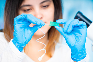 technician girl with microfluidic device LOC in microbiological lab