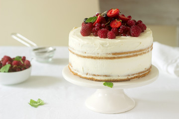 Summer home biscuit cake with curd cream, decorated with fresh berries of strawberries, raspberries and currants.