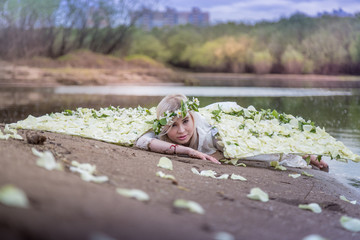Nice blonde girl with white flower wings near river