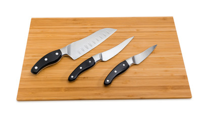 Three different kitchen knives on bamboo cutting board