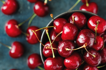 Top view of a bowl with ripe cherry over blue background. The concept of healthy organic food.