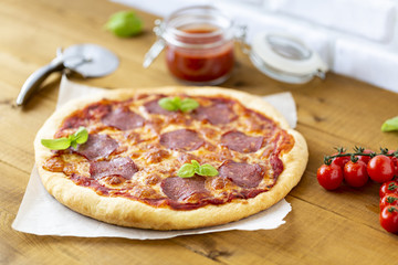 Rustic pizza with salami, mozzarella, olives and basil.
